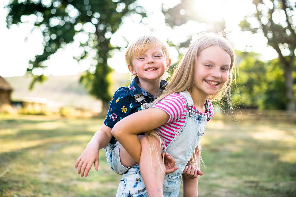 Eine große Schwester trägt stolz ihren kleinen Bruder auf ihrem Rücken.