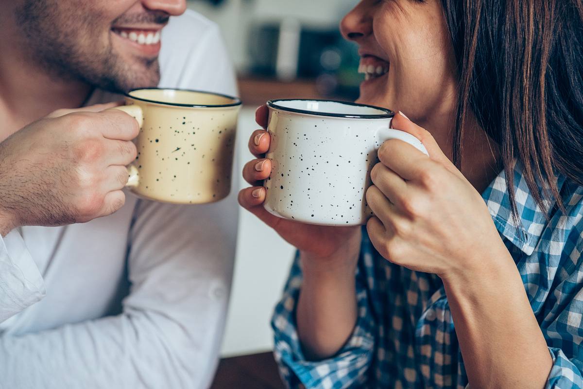 Nahaufnahme von einem lachenden Paar beim Kaffeetrinken