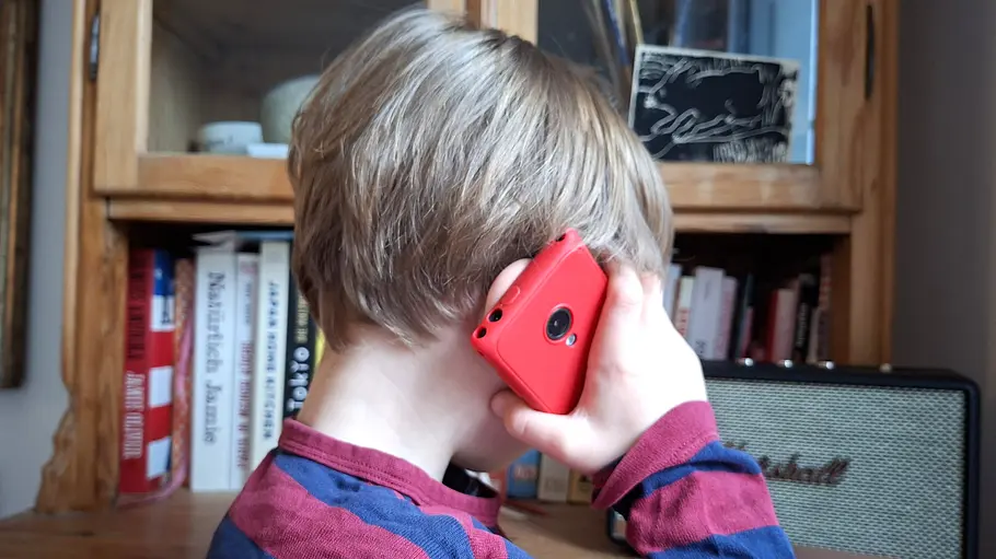 Xplora One Test Kleiner Junge mit Handy am Ohr vor Bücherschrank