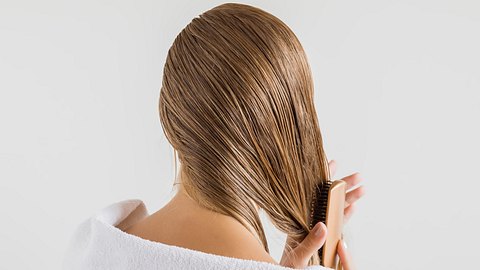 Woman in the white towel with comb brushing her wet blonde hair after shower on the gray background. Cares about a healthy and clean hair. Beauty salon concept. - Foto: FotoDuets/iStock