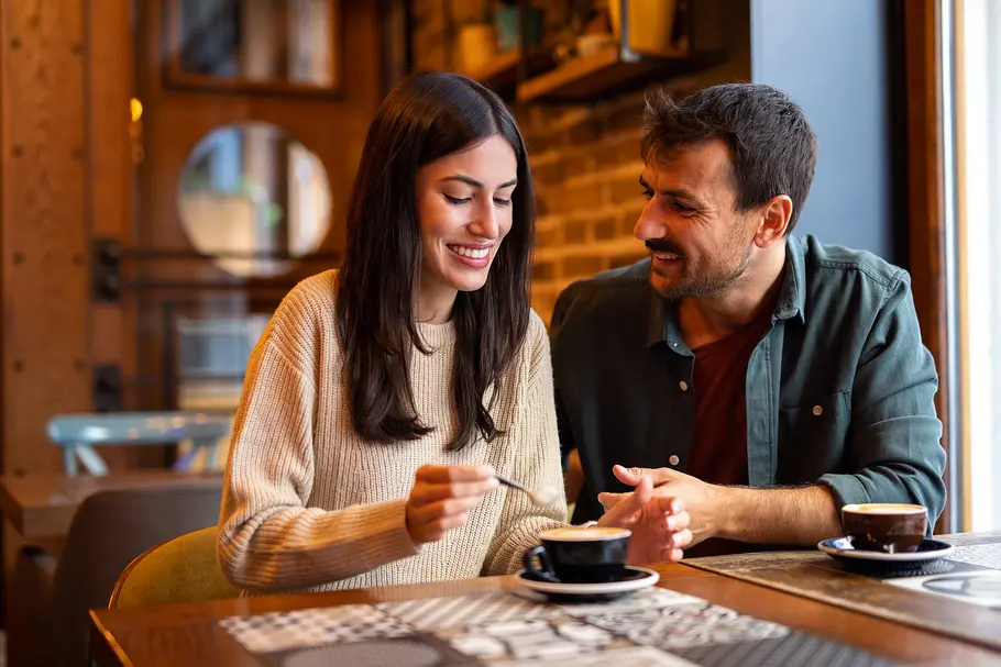5 Dinge, die deine Stimme über deine Persönlichkeit verrät Ein heterosexuelles Paar trinkt bei einem Date Kaffee in einem Café und unterhält sich.