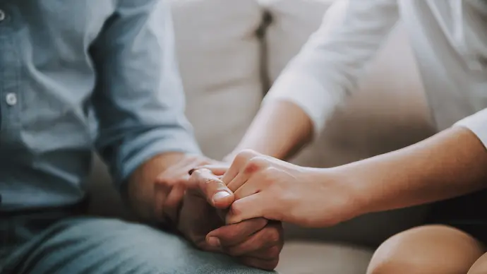 Nahaufnahme von den Händen einer Frau und eines Mannes, die sich festhalten und auf einem Sofa sitzen. - Foto: vadimguzhva/iStock