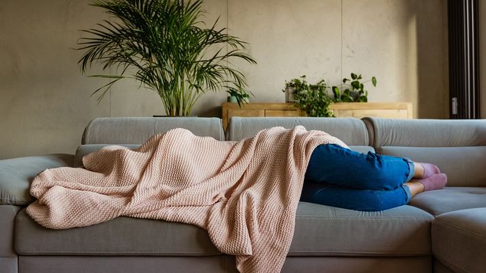 Junge Frau unter Decke auf dem Sofa. - Foto: izusek/iStock