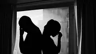 Schwarz weiß Bild von den Silhouetten eines unerkennbaren Paares, das sich Rücken an Rücken vor einem Fenster befindet. - Foto: kieferpix/iStock