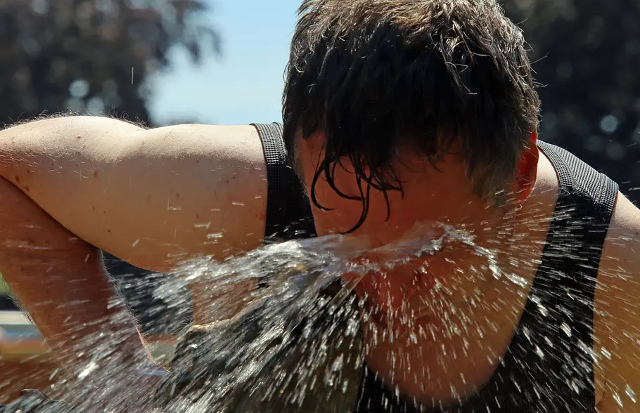 50.000 Euro Strafe! Bundesland ordnet knallharte Hitze-Regeln an Mann, der sich im Sommer mit viel Wasser aus einem Brunnen erfrischt.