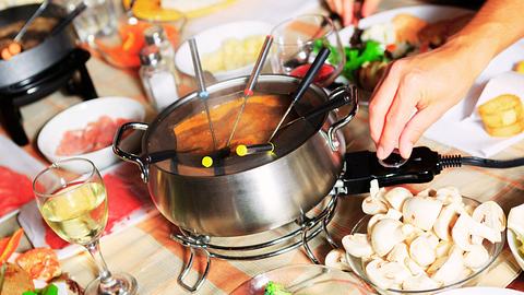 Tisch mit Fondue Topf und Zutaten. - Foto: LSOphoto/iStock