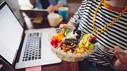 Person sitzt beim Essen zu Hause am Laptop.  - Foto: Eva-Katalin/iStock