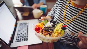 Person sitzt beim Essen zu Hause am Laptop.  - Foto: Eva-Katalin/iStock