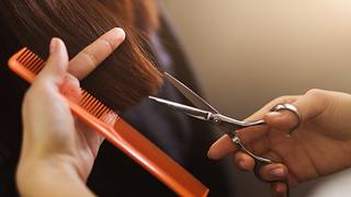 Nahaufnahme: friseurin schneidet mit der Schere braunes Haar. - Foto: Prostock-Studio/iStock