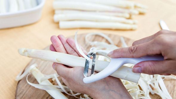 Symbolbild: Nahaufnahme von Frauenhänden, die weißen Spargel schälen - Foto: miriam-doerr/iStock