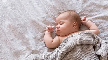 Baby schläft zugedeckt auf einer Matratze (Themenbild) - Foto: Amax Photo/iStock