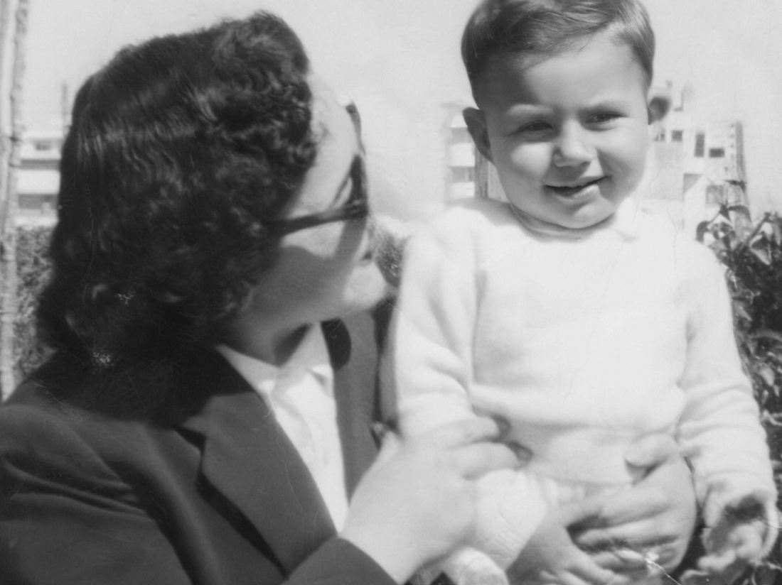 Schwarz-Weiß-Bild aus den 50er Jahren: Lächelnde Frau posiert mit ihrem KInd