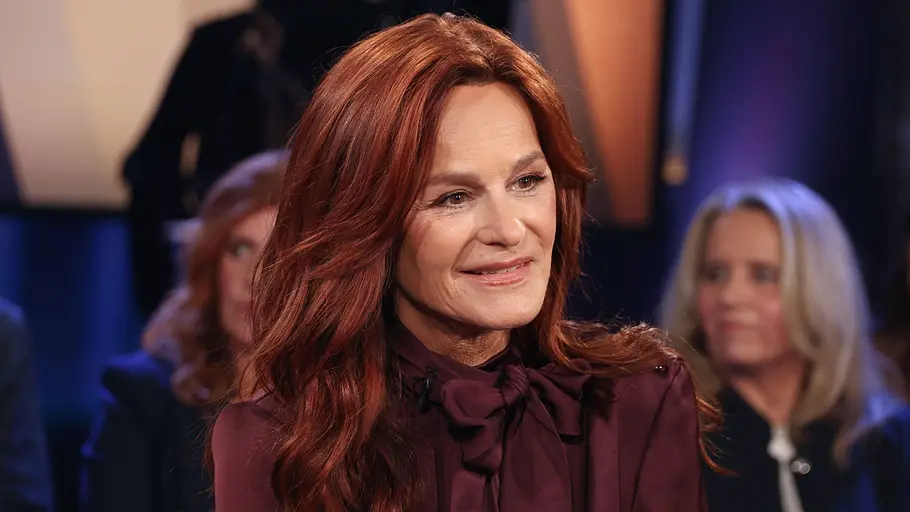 Andrea Berg sitzt in einem Sessel, blickt zur Seite und lächelt leicht.