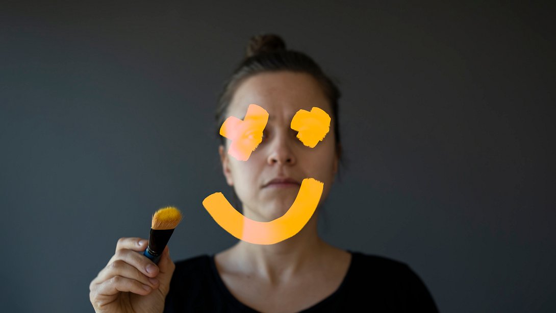 Traurige Frau malt Smiley auf einen Spiegel (Symbolbild) - Foto: Alpgiray Kelem/iStock