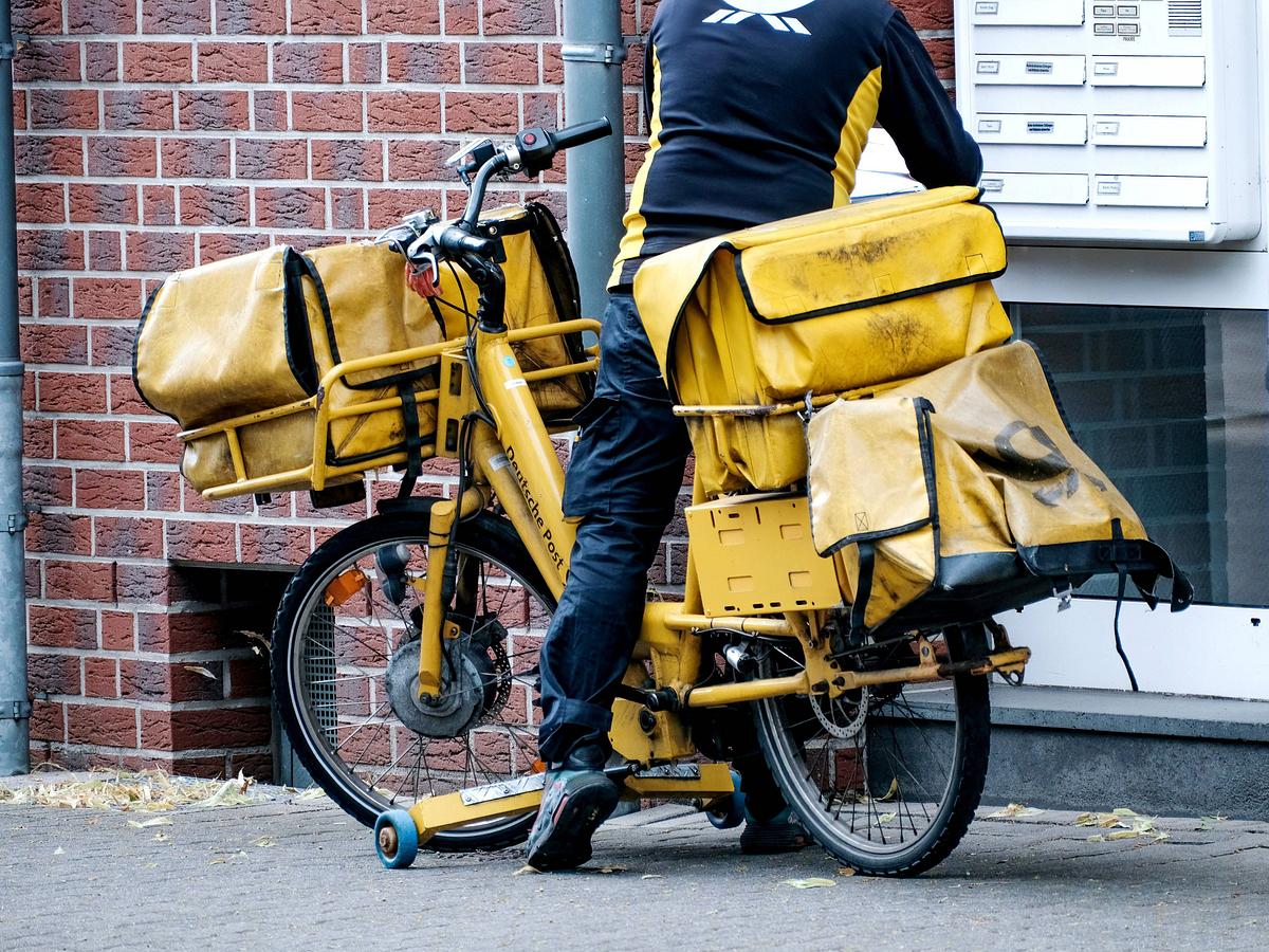 Unerkennbarer Postbote stellt Pakete und Briefe per Fahrrad zu.