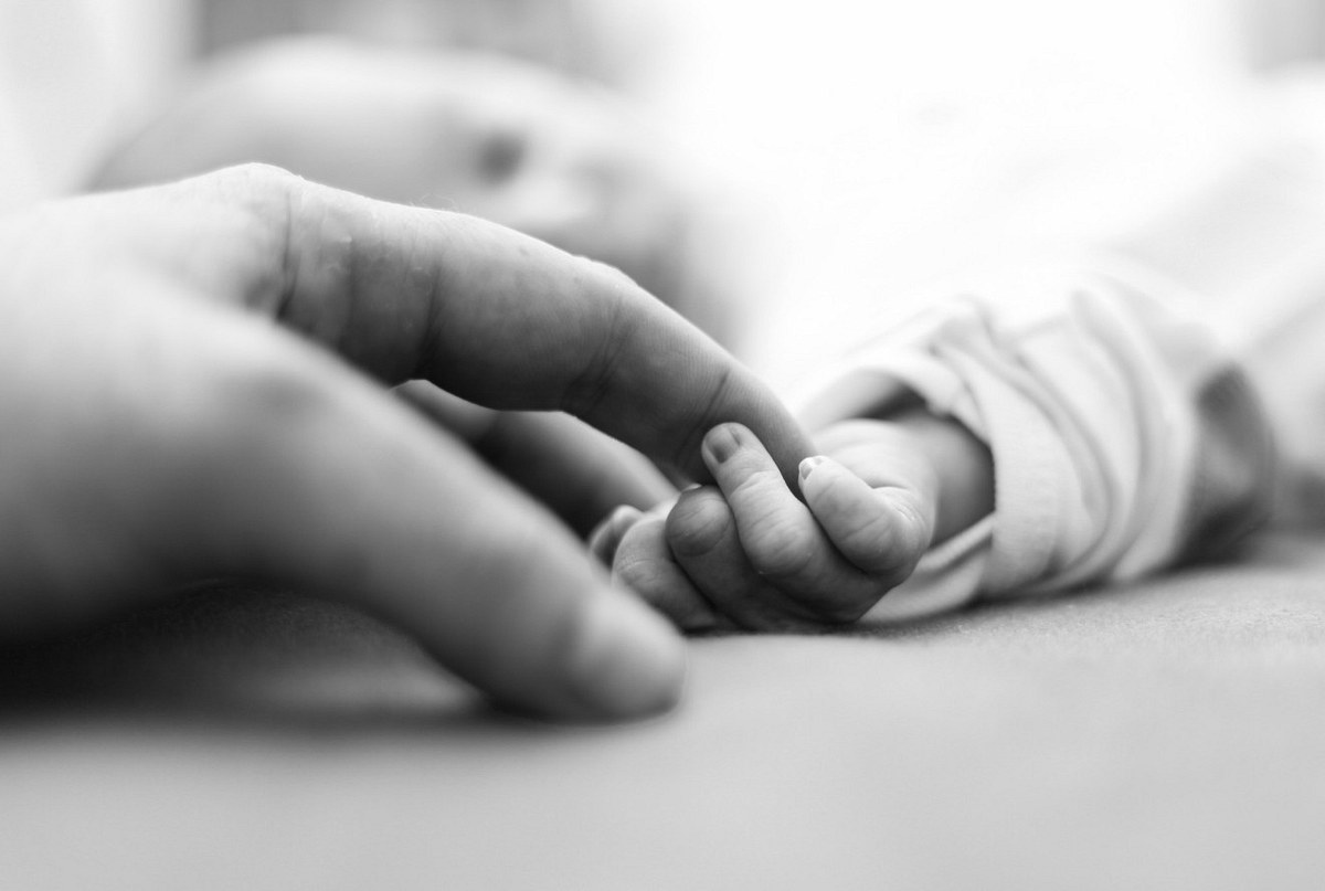 Anenzephalie: Baby Teddy lebte nur 100 Minuten Mutter berührt sanft eine die Hand ihres Babys (Symbolbild).