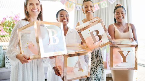 Vier Frauen halten je einen Würfel, die das Wort Baby bilden. - Foto: iStock/PeopleImages