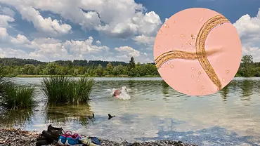 Ein Badesee mit Kleidung und Schuhen am Ufer. Ein Mensch schwimmt in einem Badesee. - Foto: saruservice/iStock