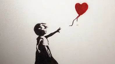 Banksy-Motiv „Girl with Balloon“: Schwarze Schablone eines Mädchens, das nach einem roten herzförmigen Ballon greift, auf hellem Hintergrund. - Foto: IMAGO / SKATA