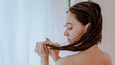 Frau trägt Haarmaske auf - Foto: iStock/ GabrielPevide