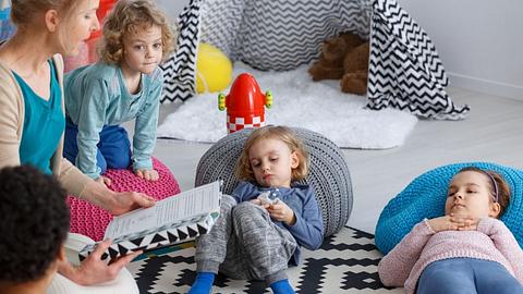 Frau liest Vorschulkindern ein Buch vor - Foto: iStock/KatarzynaBialasiewicz