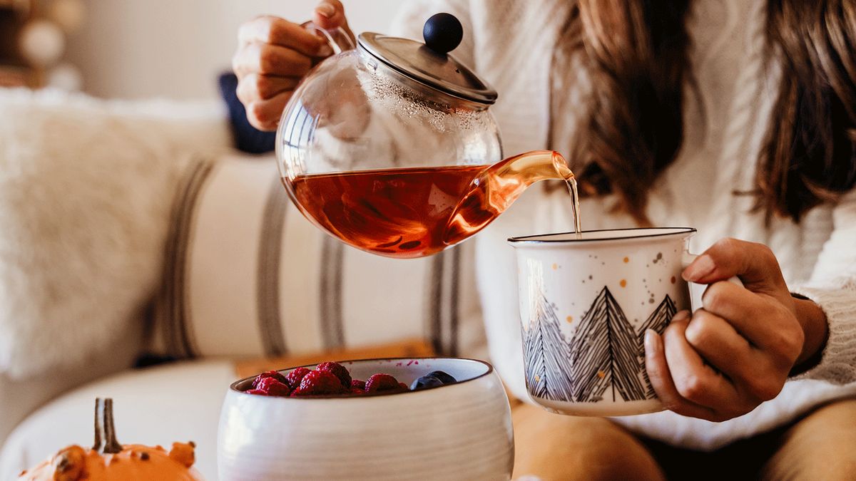 Frau gießt Tee in Tasse