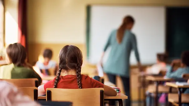 Rückansicht von einer Klasse in der Schule, im Fokus ein Mädchen mit zwei Zöpfen - Foto: iStock/Drazen Zigic