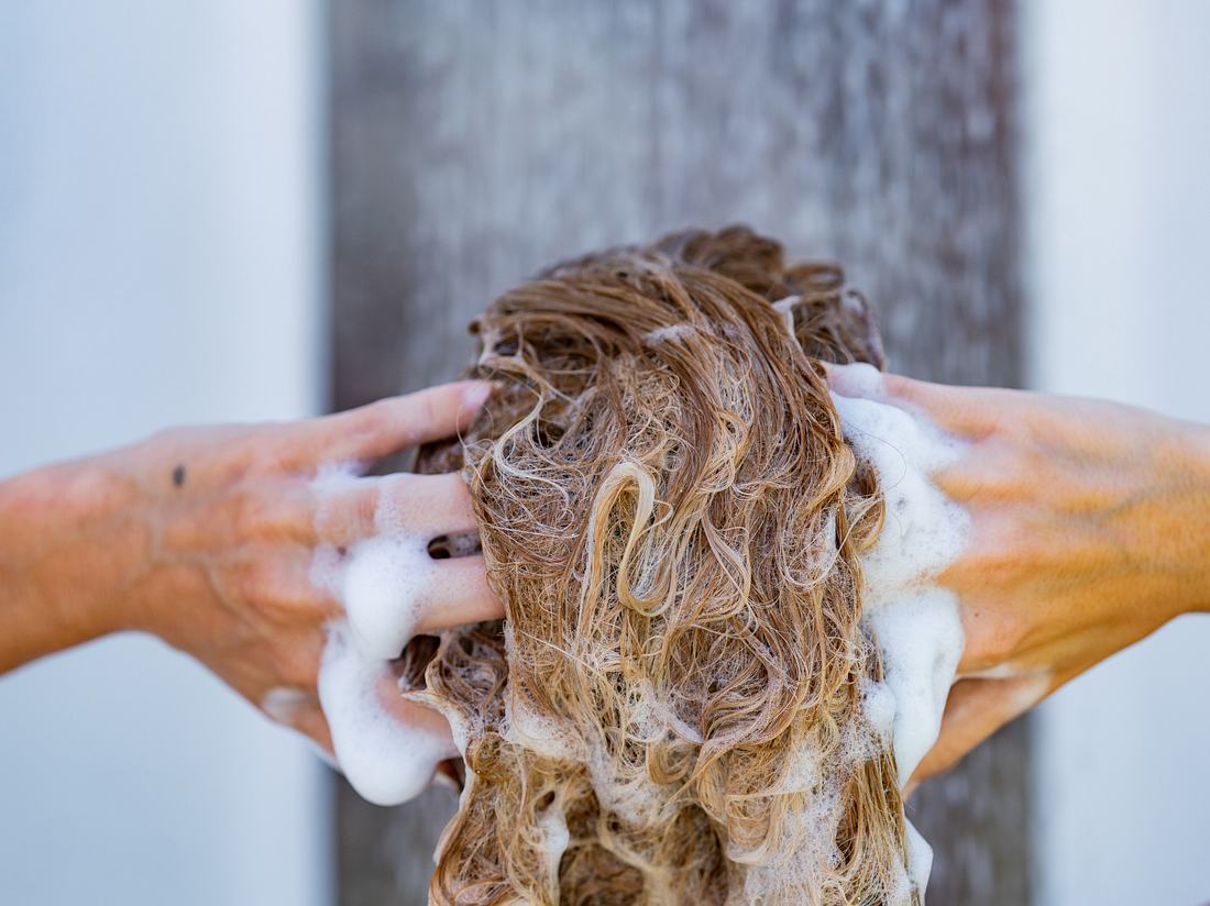 Frau wäscht sich die Haare mit Bio-Shampoo.