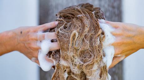 Frau wäscht sich die Haare mit Bio-Shampoo. - Foto: iStock/ StockPlanets