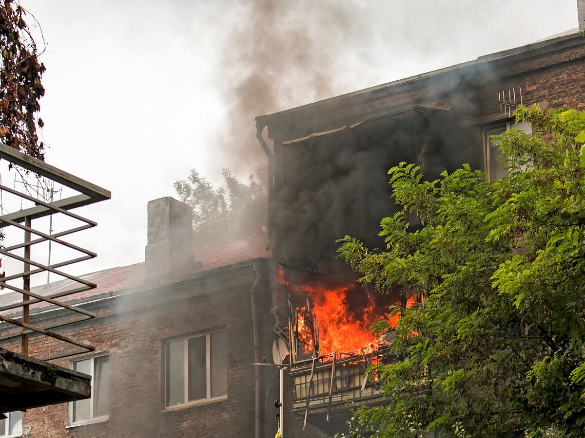 Feuer auf dem Balkon eines fünfstöckigen Gebäudes. Feuer und schwarze Rauchwolken. Rauch in der Wohnung.