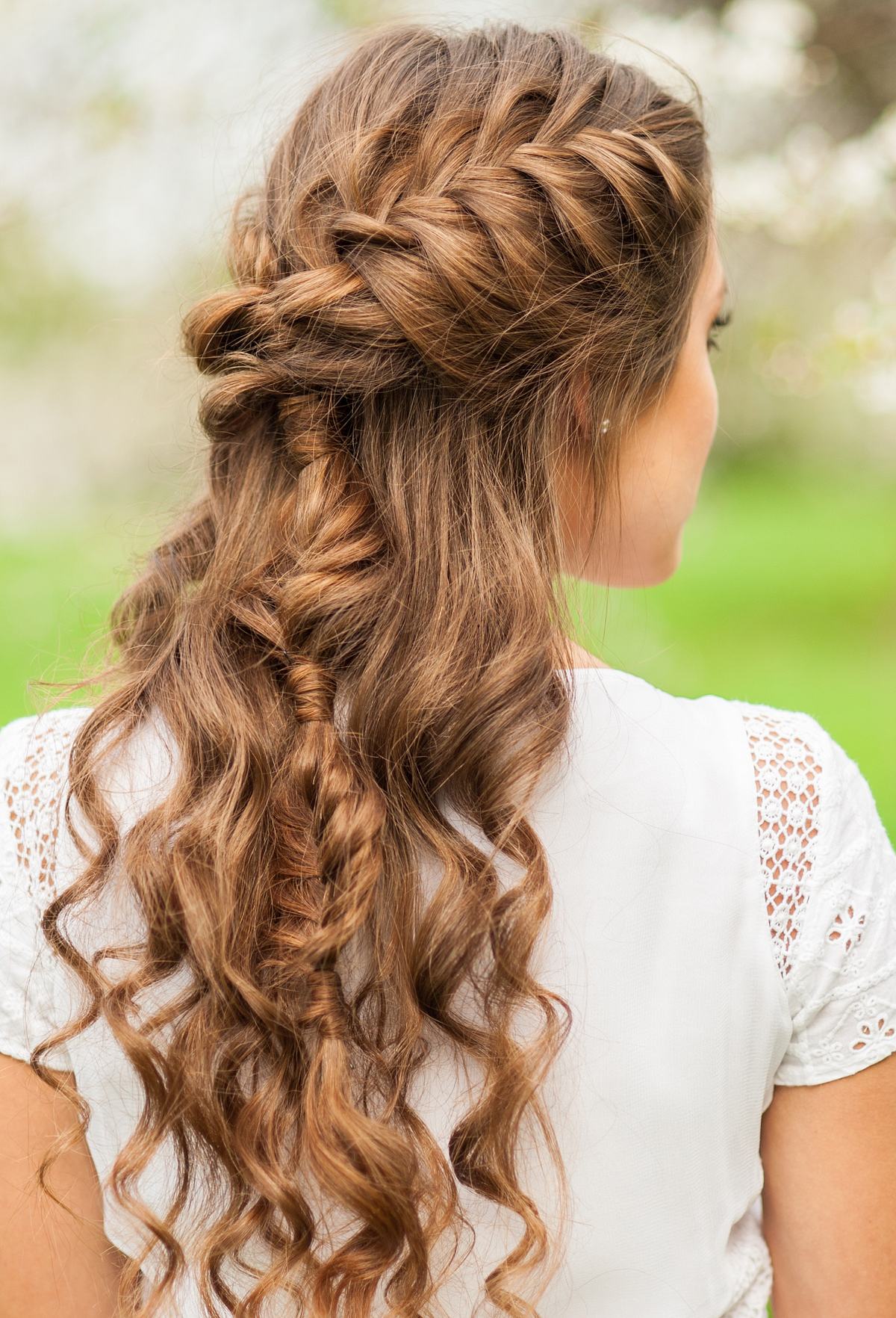 Braut mit langem Haar trägt eine romantische Hochzeitsfrisur mit einem geflochtenen Bauernzopf.