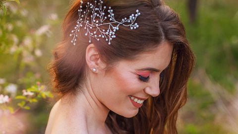 Eine wunderschöne Braut trägt eine halboffene Hochzeitsfrisur mit einer großen Haarspange an der Seite. - Foto: SrdjanPav/Getty Images
