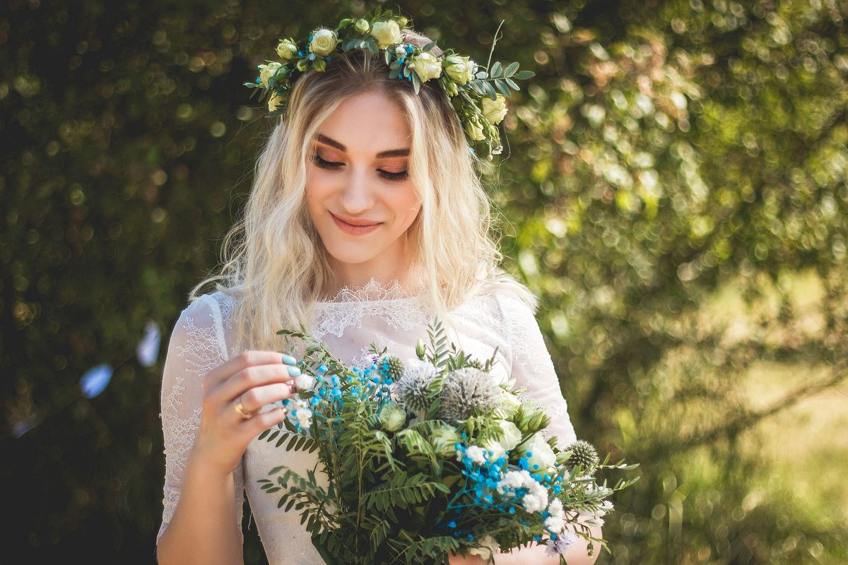 Eine Braut trägt passend zu ihrem Brautstrauß eine Hochzeitsfrisur mit Blumenkranz.