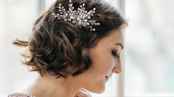 Eine Braut mit kurzem Haar kombiniert ihren Braut-Look mit einer großen, seitlichen Haarspange. - Foto: DragonFly/iStock