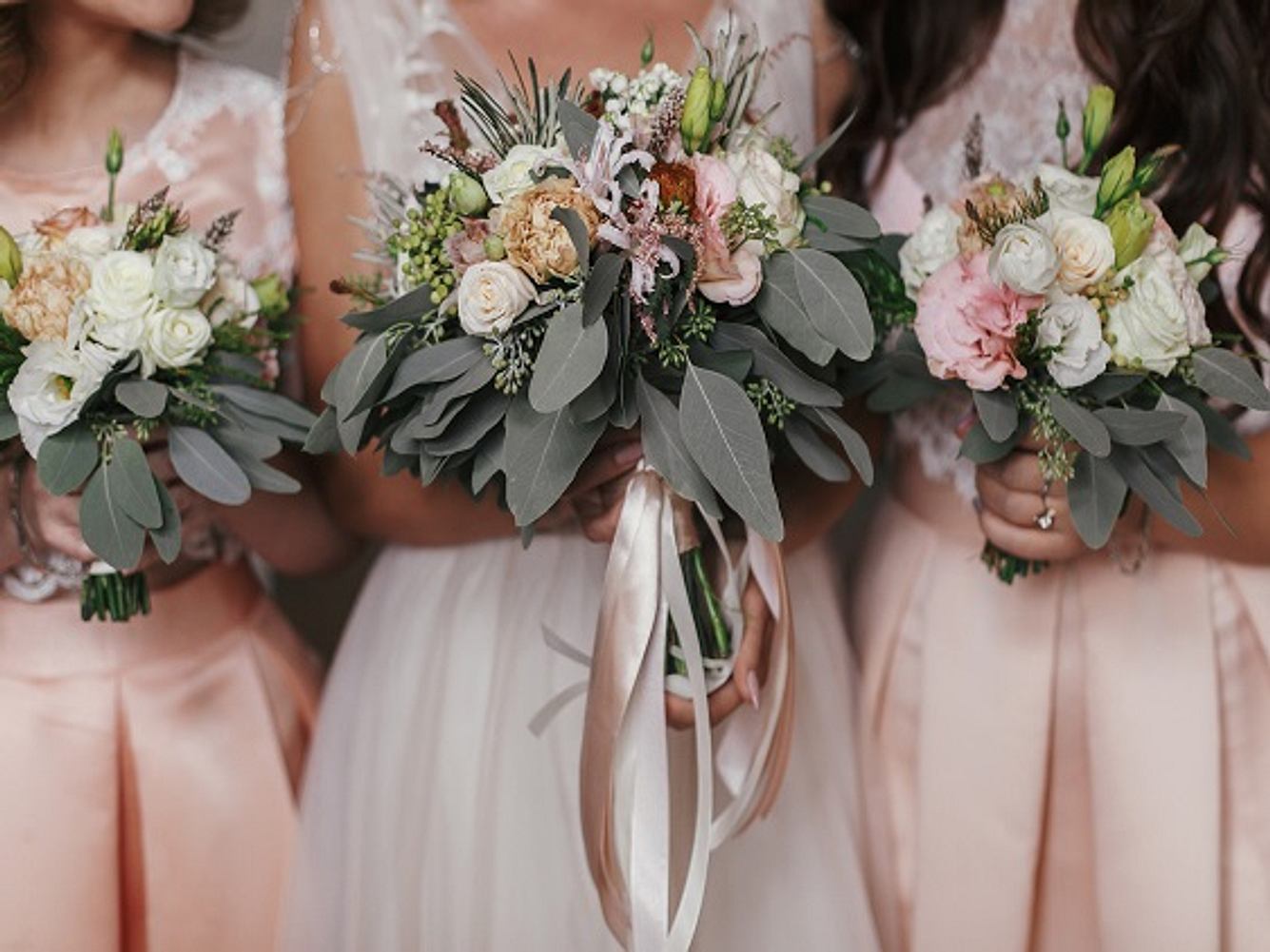 Braut und Brautjungfern in Brautjungfernkleidern und mit Blumensträußen