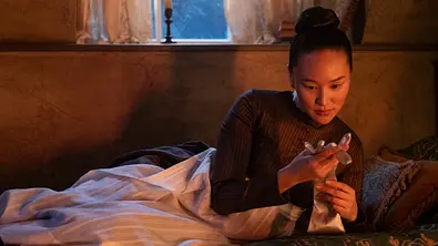 Sophie (Yerin Ha) hält einen der silbernen Handschuhe, die sie als „Dame in Silber“ beim Maskenball trug. - Foto: Liam Daniel / Netflix