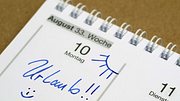 Auf einem Kalenderblatt sieht man den 10. August, beschriftet mit Urlaub, einem Emoji und einer Sonne.  - Foto: Andreas Häuslbetz/iStock (Themenbild)