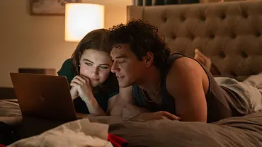 Hannah (Ella Bright) und Garrett (Belmont Cameli) in der „Off Campus“-Serie liegen auf dem Bett und schauen eine Serie. - Foto: Amazon Content Services LLC