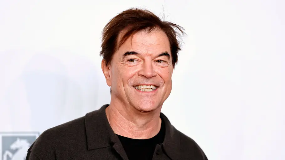 Campino Porträt vom lächelnden Campino mit braunen Haaren und dunklem Hemd vor hellem Hintergrund.