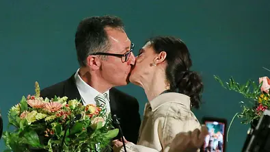 Cem Özdemir küsst seine Frau Flavia. Er hält einen Blumenstrauß in seiner Hand. - Foto: IMAGO / dts Nachrichtenagentur