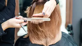 Eine Frau mit braunem Haar wird beim Frisur das Haar geschnitten.  - Foto: okskukuruza/iStock (Themenbild)