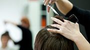 Linke Hand mit Kamm hält kurze Haare hoch, rechte Hand mit Schere schneidet ins Haar. - Foto: hoozone/iStock (Themenbild)