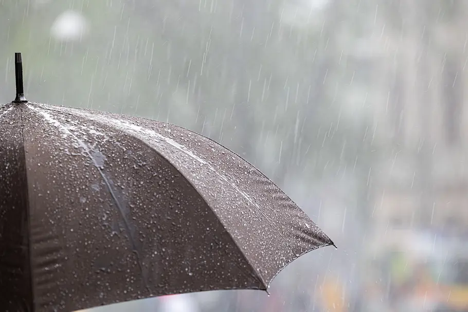 Dauer-Regen statt Hitzewelle: so lange hält die nächste Regenphase an Grauer Regenschirm unter starkem Regen, verschwommener Hintergrund, Symbolbild für regnerisches Wetterkonzept.