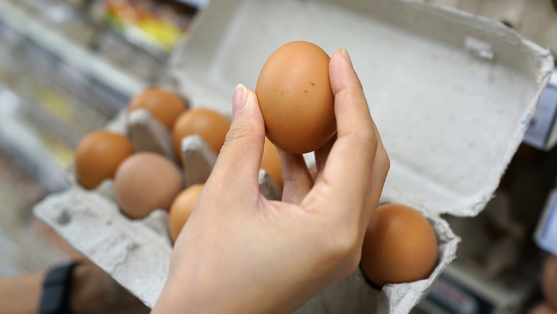 Frau, die frische braune Eier aus dem Eierkarton nimmt - Foto: tylim/iStock