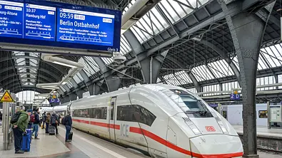 ICE-Zug der Deutschen Bahn steht in einer Bahnhofshalle am Bahnsteig, während Reisende auf die Abfahrt warten - Foto:  IMAGO / Joko