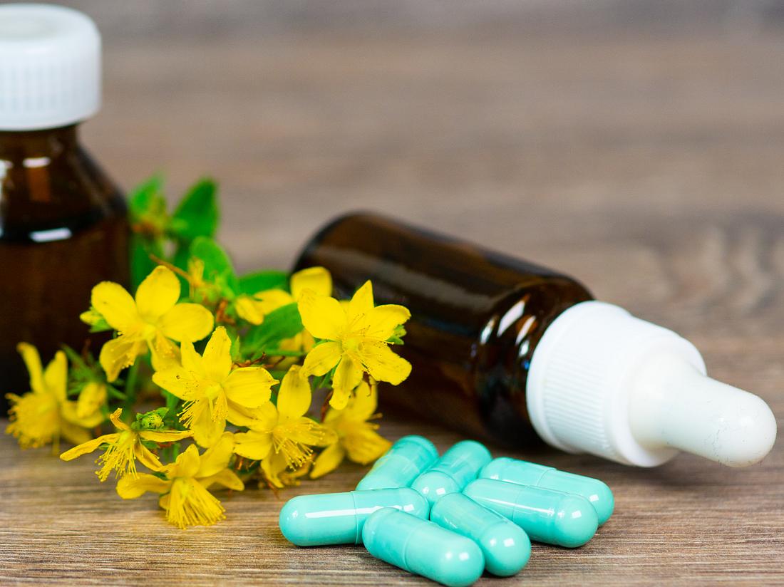 Bio-Kräutermedikamente in grünen Kapseln und braunen Glasflaschen