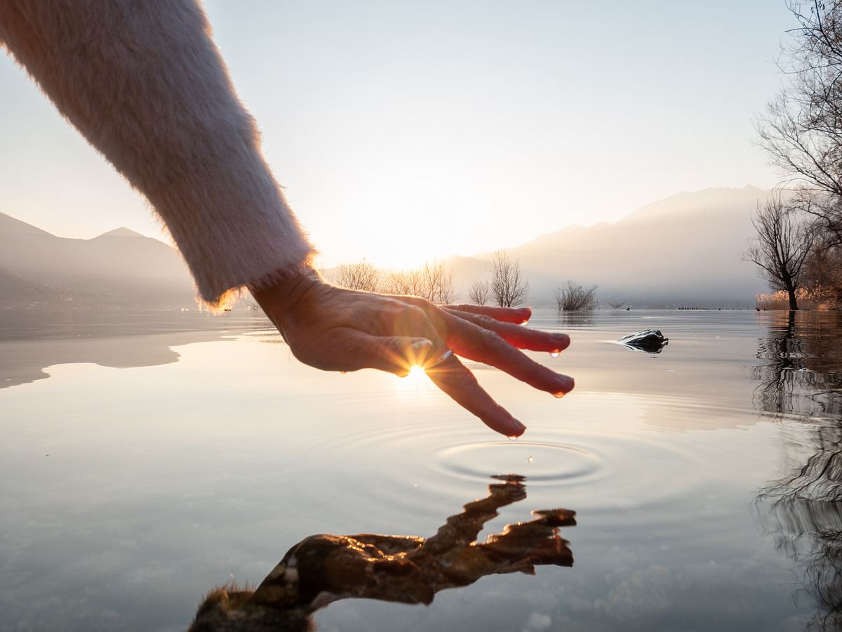 Detail der Hand berührenden Wasseroberfläche des Sees bei Sonnenuntergang.