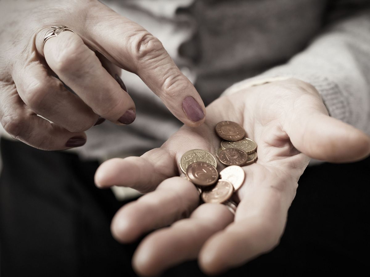 Nahaufnahme einer älteren Frau, die Kleingeld in der Hand zählt