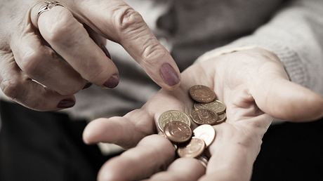 Nahaufnahme einer älteren Frau, die Kleingeld in der Hand zählt - Foto: grinvalds/iStock