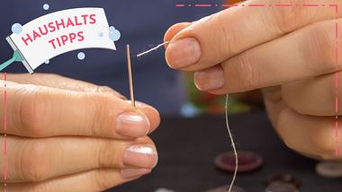 Weibliche Finger halten eine Nadel und einen Faden. - Foto: Tomasz Majchrowicz/iStock 
